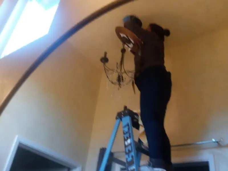Electrician installing a chandelier in a St. George residence